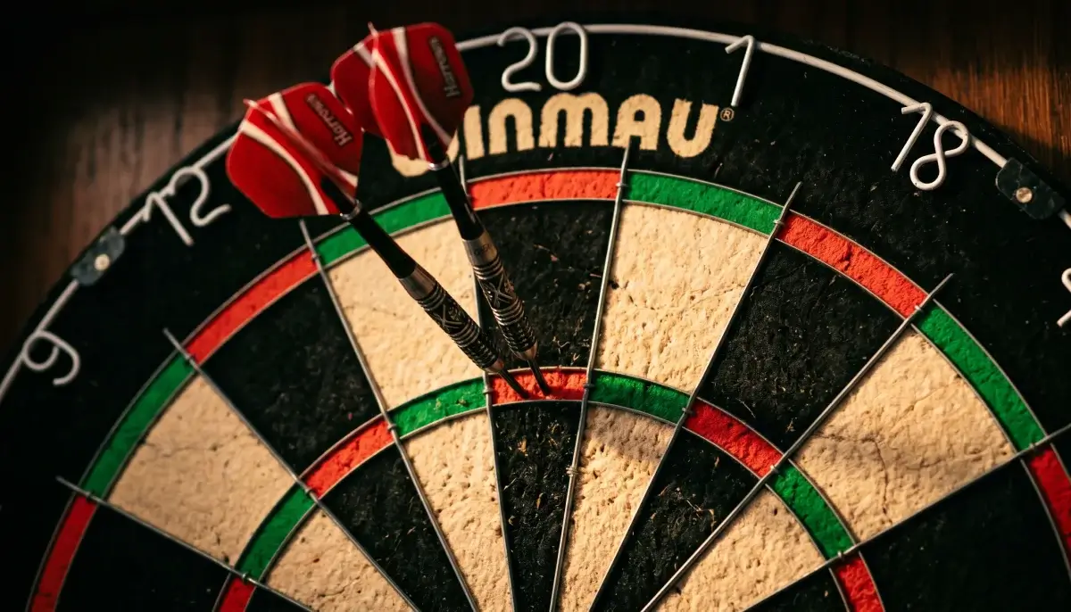 Nahaufnahme eines Dartboards mit drei Pfeilen in der Triple-20 bei einem professionellen Darts-Turnier